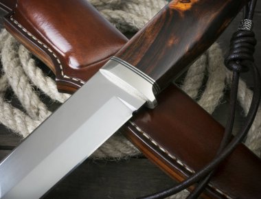 Kahverengi ahşap arka planda el yapımı avcı bıçağı.