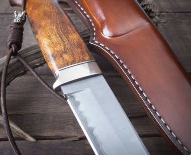 Kahverengi ahşap arka planda el yapımı avcı bıçağı.