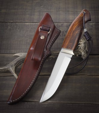 Kahverengi ahşap arka planda el yapımı avcı bıçağı.