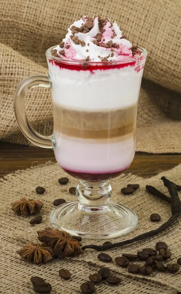 Coffee Latte. Coffee with whipped cream topping in a tall glass on a wooden background with burlap