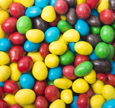 Renkli şekerler doku arka planını kapatın. Gökkuşağı renkli şeker çikolata parçaları bir kase (seçici odak kaplı)