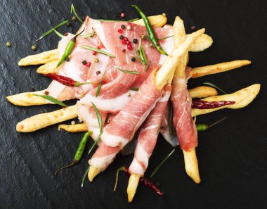 Grisini ekmek sopa ile prosciutto biberiye, siyah bir zemin üzerine biber 