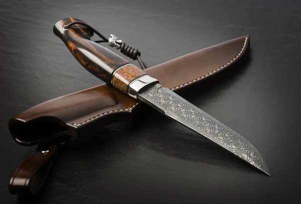 Hunting knife from Damascus mosaic with mammoth tusk on a black background. Leather Sheath Handmade