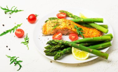 Fırında somon kuşkonmaz ve domates ile otlar ile süslenmiş