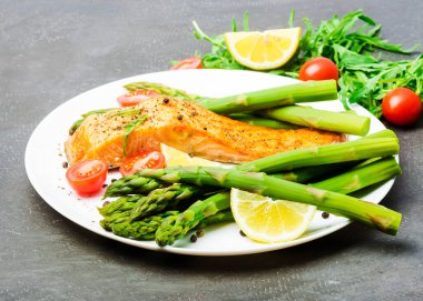 Fırında somon kuşkonmaz ve domates ile otlar ile süslenmiş