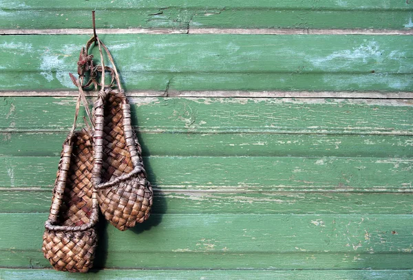 Stare buty bast (tradycyjne obuwie rosyjski) na zielono drewniane — Zdjęcie stockowe