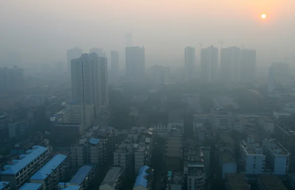 Soluppgången genom smog i en modern kinesisk stad Stockbild