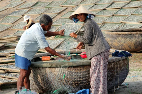 Muine, Vietnam - 13 Feb 2009: Vietnamesiska fiskare kontrollera fiskenät nära rund wicker båt (Thung chai). Utvinning av skaldjur är den huvudsakliga verksamheten i kustbyarna i Vietnam — Stockfoto