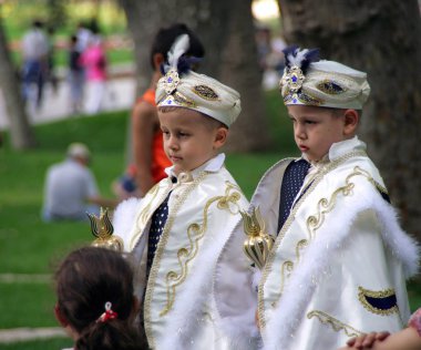 ISTANBUL, TURKEY - JUN 15, 2008: Two boys dressed as Turkish sultans in the park of Topkapi palace clipart