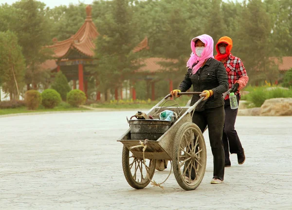 INCHUAN, INNER MONGOLIA - JUl 6, 2011: Chinese women walking on the street during a sandstorm. In recent years in Inner Mongolia (North China) sandstorms occur more often, especially in spring and summer — Stock Photo, Image