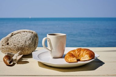 Terasta ayçöreği ve meyveli kahve fincanı ve güneşli bir günde deniz manzarası. Tatil, tatil ya da yaz tatili kavramı.