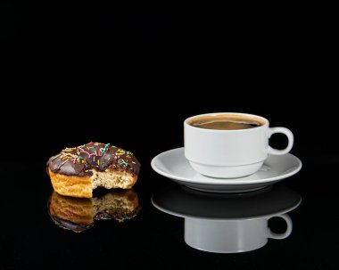 Isırılmış çörek ve siyah arka planda kahve fincanı.