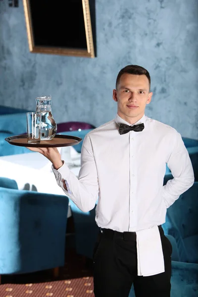 一位年轻貌美的侍者手里拿着一盘水壶. 餐饮业的概念。 餐饮业的工作人员. — 图库照片