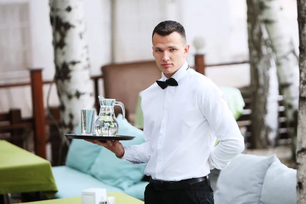 一位年轻貌美的侍者手里拿着一盘水壶. 餐饮业的概念。 餐饮业的工作人员. — 图库照片