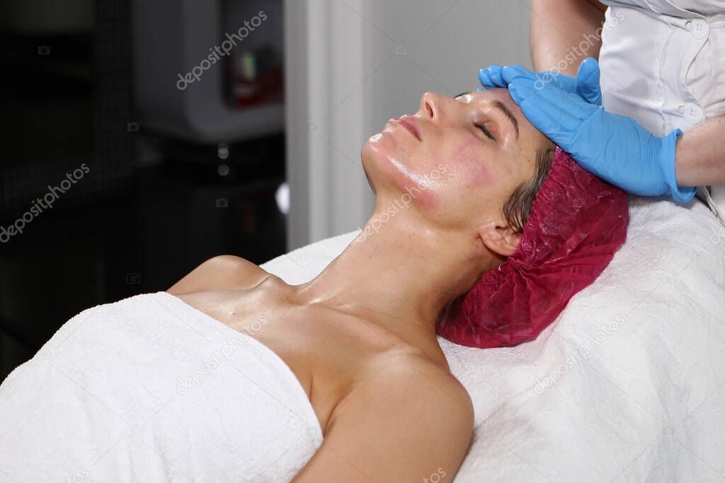 Beautician does facial massage in a cosmetology clinic. Hands in gloves. Beauty and health concept.