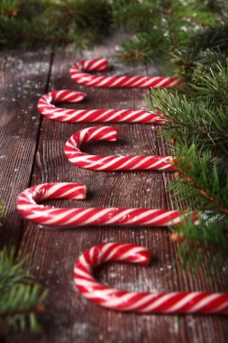 Tahta bir arka planda ve köknar dallarıyla karamel şeklindeki şeker. Bir yazı ya da etiket yerleştir. Yeni yıl ya da noel tatili konsepti bulanık.