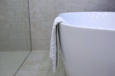 Ayaklar için beyaz bir havlu küvetin kenarında asılı duruyor. Fotoğraf, banyonun iç tarafında. Yukarıdan bak. Otel işi konsepti.