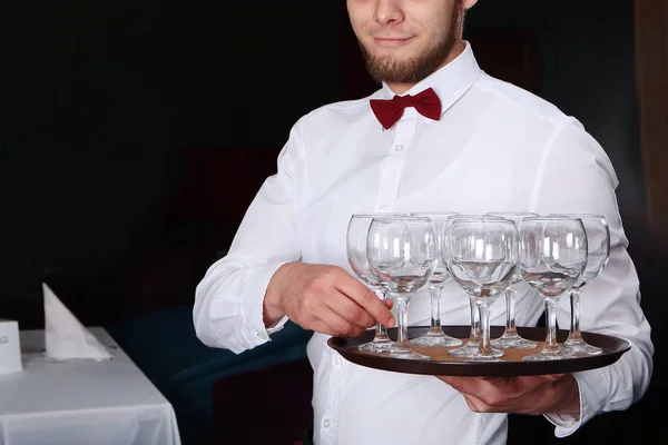 Un joven camarero trajo copas de vino en una bandeja. Foto sin rostro en el interior del restaurante . — Foto de Stock