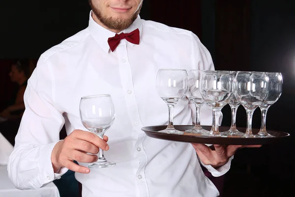 Camarero joven con camisa blanca y pajarita. Foto sin rostro sobre fondo oscuro en el interior del restaurante . — Foto de Stock