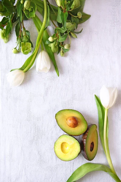 Reife Avocado und weiße Blüten auf einer weißen Serviette. Blick von oben. Kopierraum. — Stockfoto