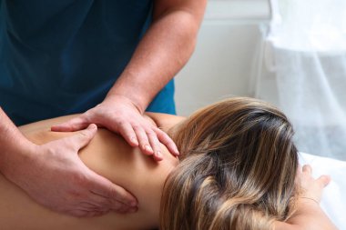 Bir osteopat doktor elleriyle hastanın sırtında manipülasyon yapar. Sağlığın korunması ve önlenmesi kavramı. Uzayı kopyala Kliniğin içinde bir fotoğraf var. Makro fotoğraflı.