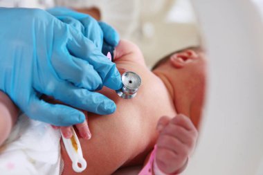 Yeni doğanların hayatlarını kurtarıyorum. Hastanedeki resüsitasyon. Yeni doğmuş bebek tıbbi atıcıda. Bir doktorun elinde steteskop..