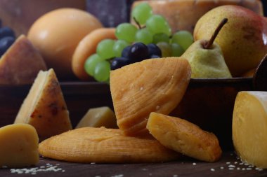 Siyah arkaplandaki peynir ve meyveden hareketsiz yaşam. Yan görüş. Durgun yaşam ya da resimleme kavramı.