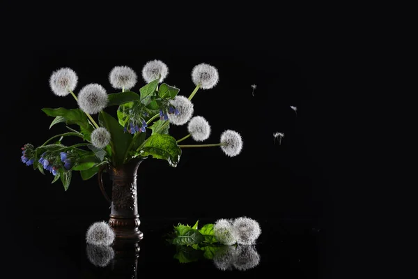 Een boeket bloemen van paardebloemen en blauwe en roze weidebloemen op een zwarte achtergrond. Een boeket wilde bloemen. Een kopie van de ruimte. Een concept van stilleven. — Stockfoto