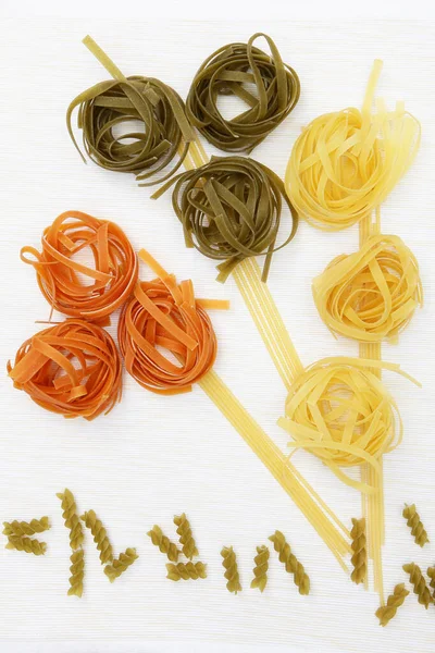 Pastaproducten nesten van verschillende kleuren op een witte achtergrond. Kopie van de ruimte.Concept stilleven. — Stockfoto