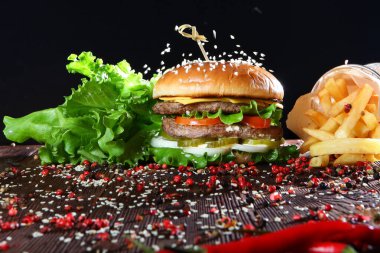 Hamburgerin üzerine susam ezmesi ve iki pirzola. Siyah arka planda durgun yaşam kavramı. Boş alan.