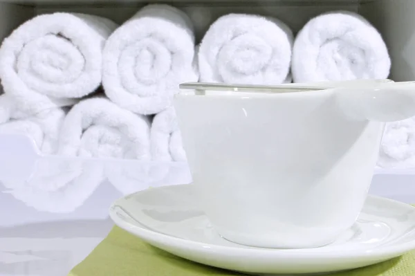 Šálek kávy na pozadí jednotlivých ručníků, složený válec. Kotsept pohodlí a servis pro zákazníky kosmetické skříně. — Stock fotografie