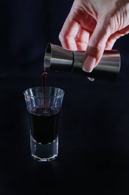 Bir bardak dolusu alkollü içeceği bardağa dolduruyorum. Siyah arkaplandaki fotoğraf. Uzayı kopyala Hayat konsepti