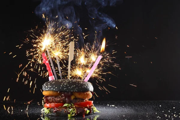 Siyah çörekli hamburger, maytap ve bayram için mum. Tatil sandviçi için çok güzel tasarlanmış. Boşluğu kopyala.