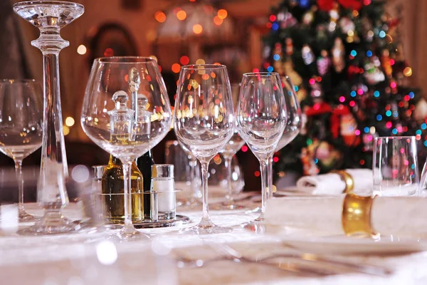 Стіл для святкування Нового року або Різдва. Різдвяна ялинка поза фокусом. Порожні скляні келихи для вина . — стокове фото
