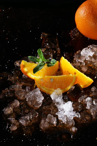 Orange slices with ice lie on a black background. The view from the top. Copy space. — Stock Photo, Image