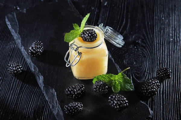 Jar of honey and blackberry on a black background. View from above. Still life concept. Copy space. Macro photo. — Stock Photo, Image
