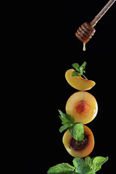 Honig tropft vom Stock auf die Aprikosen. Foto auf schwarzem Hintergrund. — Stockfoto