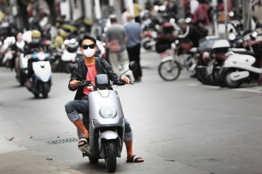 Çin 'de Coronavirus. Salgın tehdidi var. Motosikletli genç bir adam yüzünde tıbbi bir maskeyle şehrin sokaklarında geziyor. Sağlık koruması.
