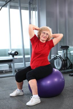 An elderly woman is engaged with a fitness ball. Retired healthy and active lifestyle concept.