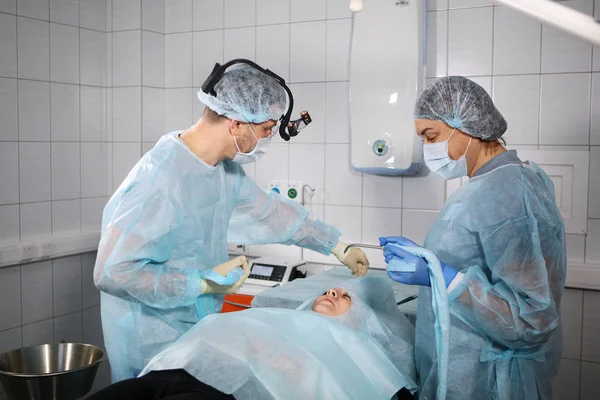 Dental surgeon and assistant prepare the patient for anesthesia. Photo in the operating room. View from above. — Stock fotografie