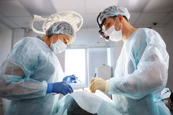 Chirurgul, dentistul și asistenta medicală efectuează o operație asupra pacientului. Conceptul de menținere a sănătății și frumuseții . — Fotografie, imagine de stoc