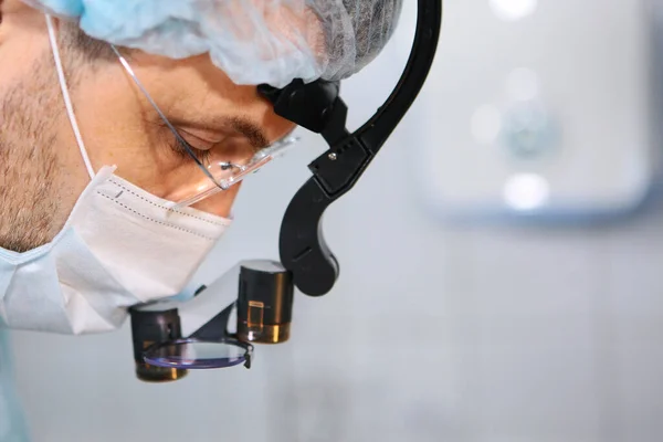 Close-up of a dentist surgeons face with a microscope in glasses. Binocular glasses. Copy space. — Stock fotografie