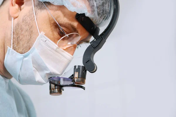 Close-up of a dentist surgeons face with a microscope in glasses. Binocular glasses. Copy space. — Stock fotografie