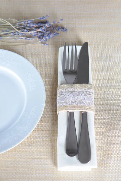 Table setting in beige for the holiday. The knife and fork are connected by a fabric ring with lace. Concept of restaurant and hotel business. — Stock Photo, Image