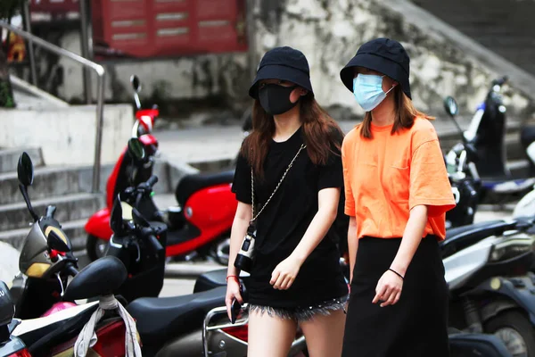 Two Chinese women are walking down the street with gauze masks on their faces. The threat of a coronavirus epidemic in China. Covid-19