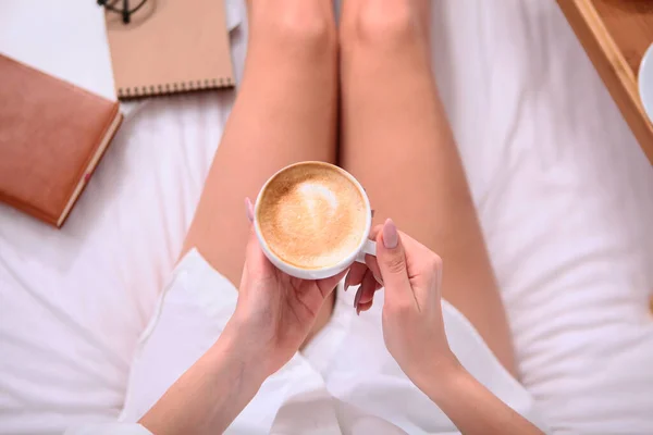 White Cup with coffee and milk in women s hands. The view from the top. Out of focus. Photo without face, only hands.