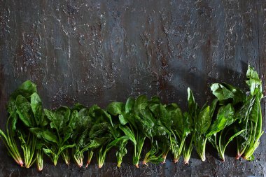Tahta desenli arka planda kökleri olan ıspanak yaprakları. Koyu kahverengi ve mavi renkler. Üst Manzara. Boşluğu kopyala