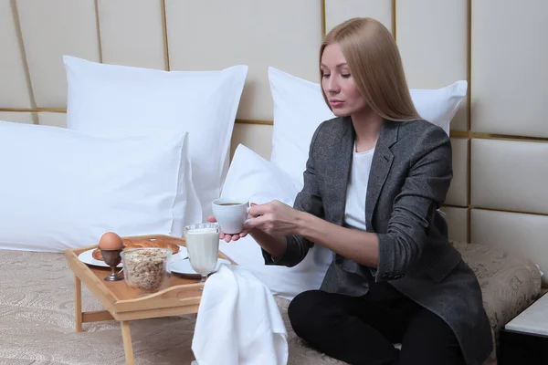 Una Rubia Ropa Negocios Está Sentada Una Cama Una Habitación — Foto de Stock