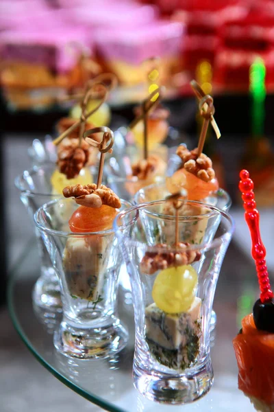 Cheese canapes with walnuts in a glass glass. Catering services for events. Photo on a dark background. Copy space. Top view.