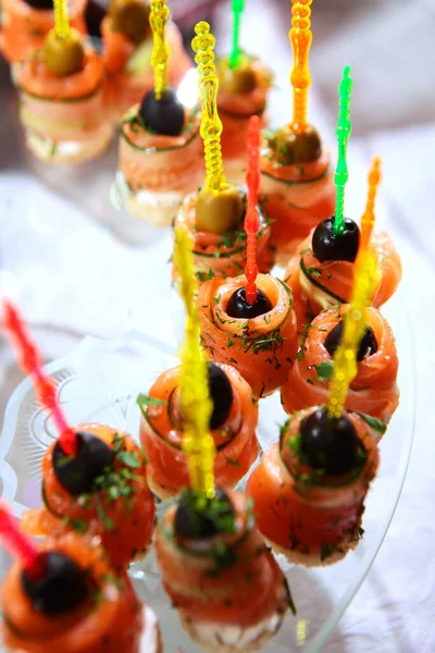 Lots of red fish canapes with cucumber and olive. Catering services for events. Field service. Photo on a dark background. Copy space. Top view.